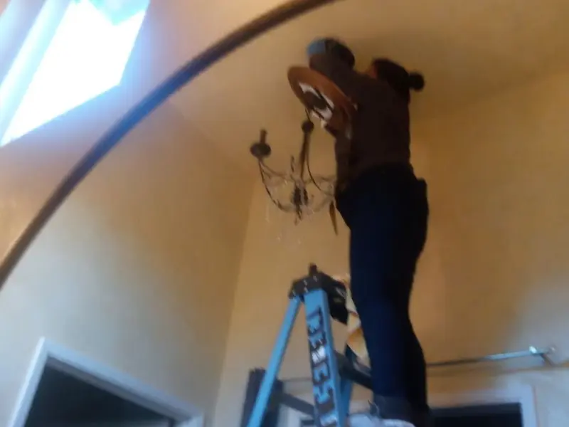 Electrician installing a chandelier in a Woodlawn residence
